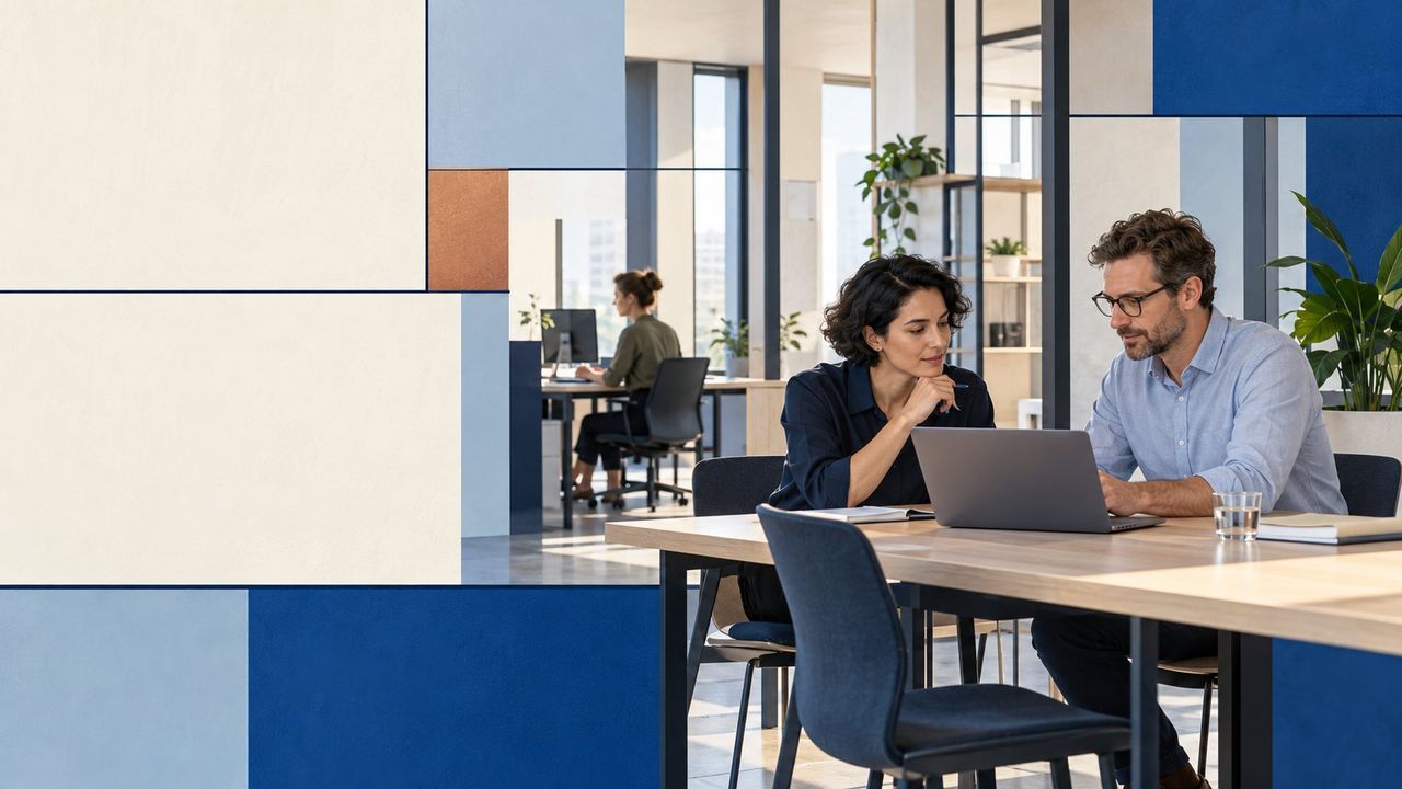 Twee collega’s overleggen aan een tafel met een laptop; de omgeving is opgebouwd uit heldere vlakken
